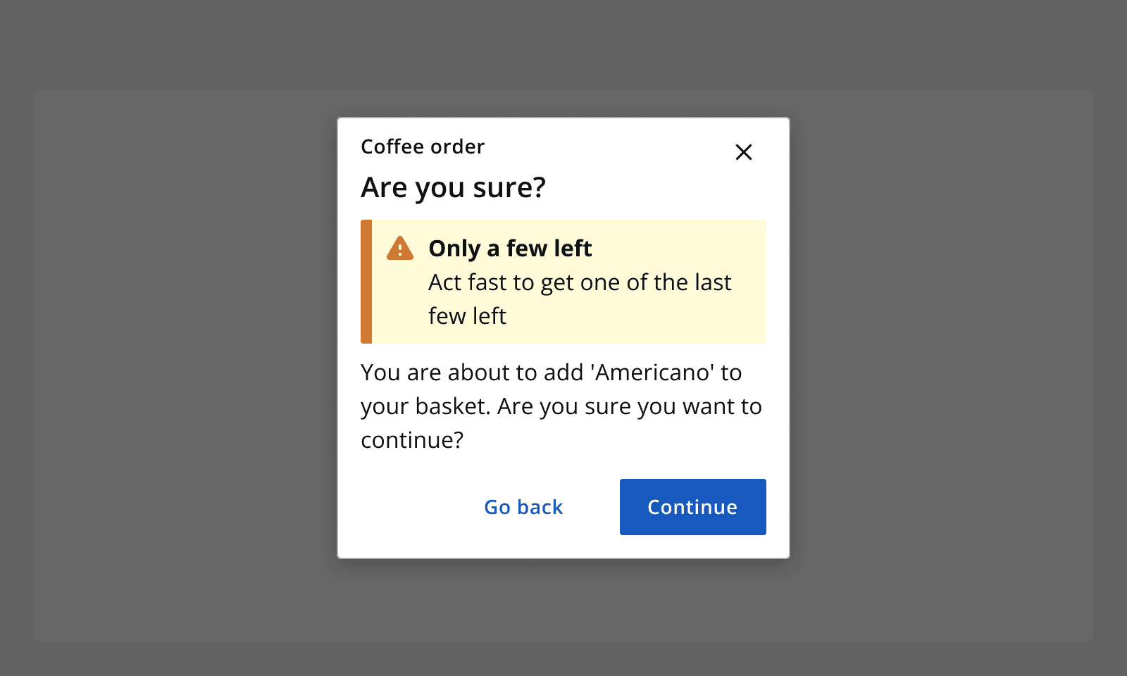 An example dialog for a coffee order asking if the user is sure they want to continue adding the product 'Americano' to their basket. It contains a warning alert that says 'Only a few left'.